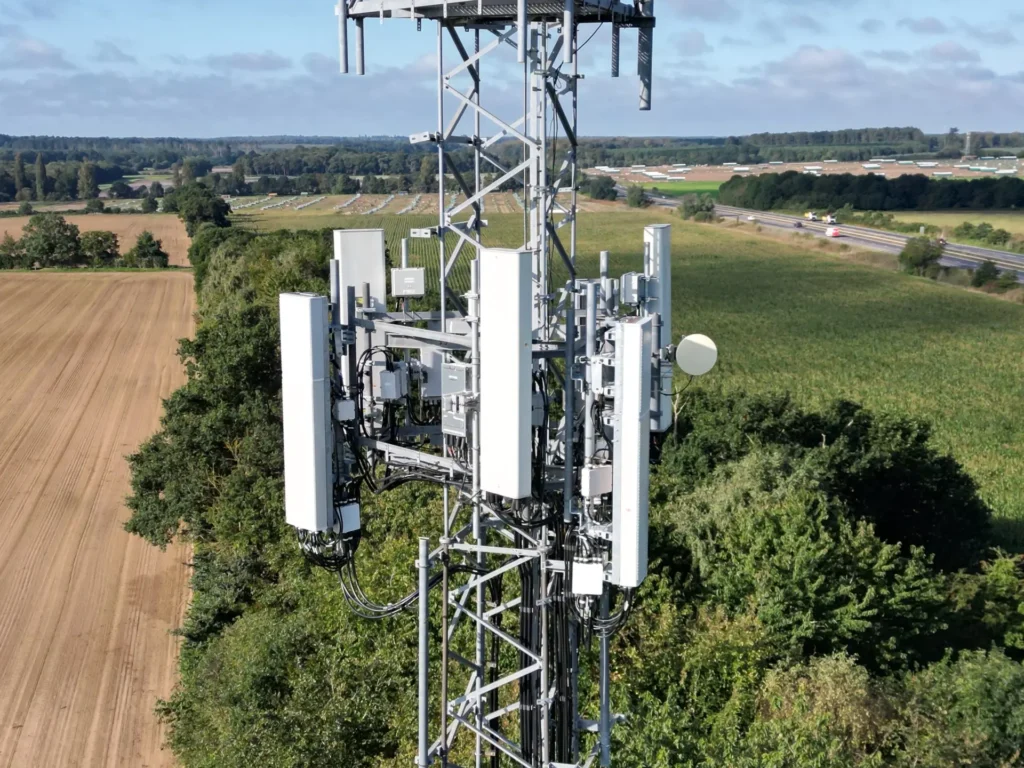 Drone view of antennas and equipment on a telecoms mast beside a motorway