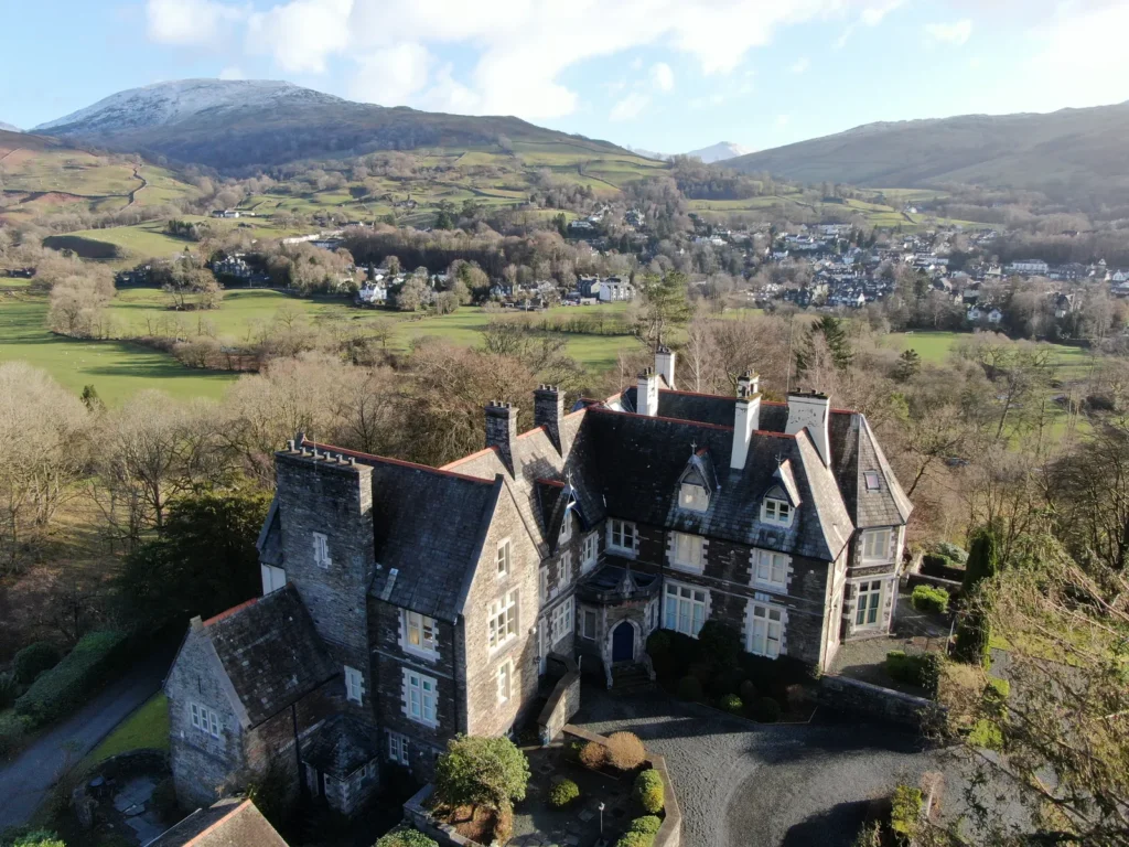 Aerial view of a stone country house with hills behind