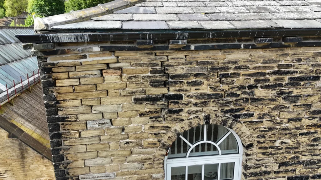 Drone image of a stone façade with bulging and stained masonry